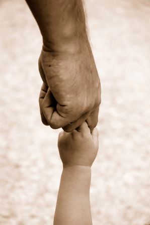 An older hand grabbing the hand of a younger child